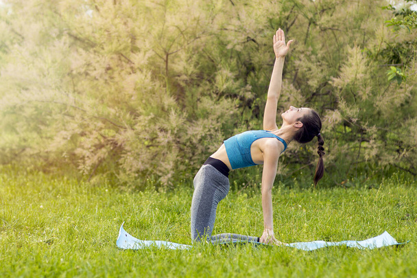 Young Caucasian woman doing yoga in the Park. - Photo, image