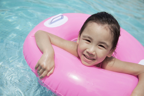 meisje zwemmen in het zwembad met een roze buis - Fotoğraf, Görsel