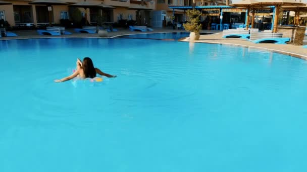 Drone flying over a pool in Egypt where a women is lying on a mattress - Záběry, video