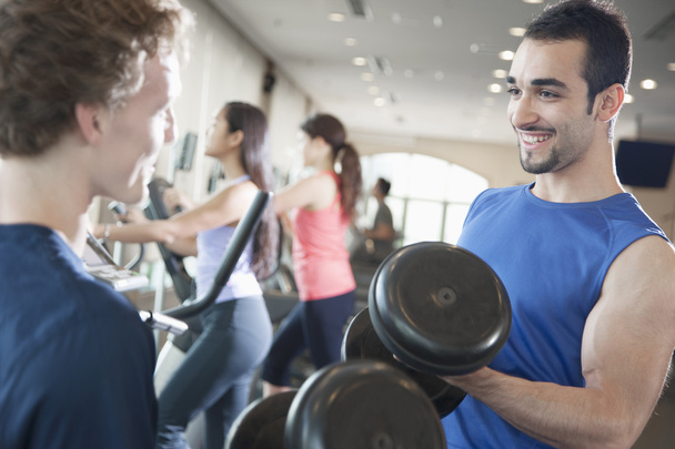 erkekler gülümseyen ve spor salonunda ağırlık kaldırma - Fotoğraf, Görsel
