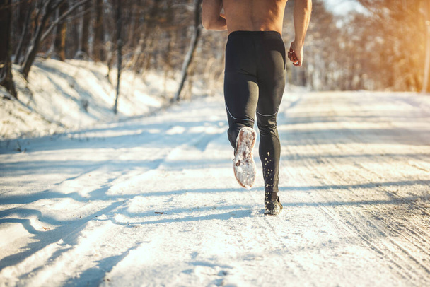 Primo piano delle gambe di un maschio è in esecuzione nella strada forestale durante l'allenamento invernale fuori
.  - Foto, immagini
