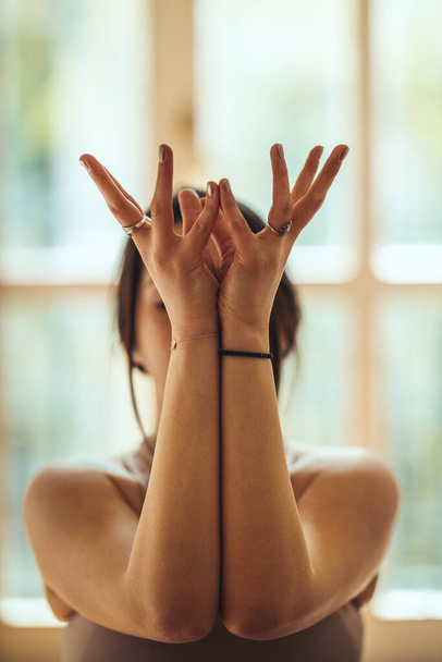 Junge Frau macht Yoga während der Coronavirus-Pandemie im heimischen Wohnzimmer. Sie meditiert in der Morgensonne. - Foto, Bild