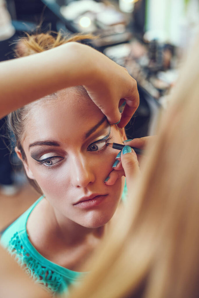 make-up artysta, który nakłada makijaż na pięknej młodej kaukaskiej kobiety. - Zdjęcie, obraz