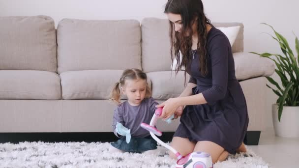 Mother and kid are playing with a vacuum cleaner toy in a living room - Video