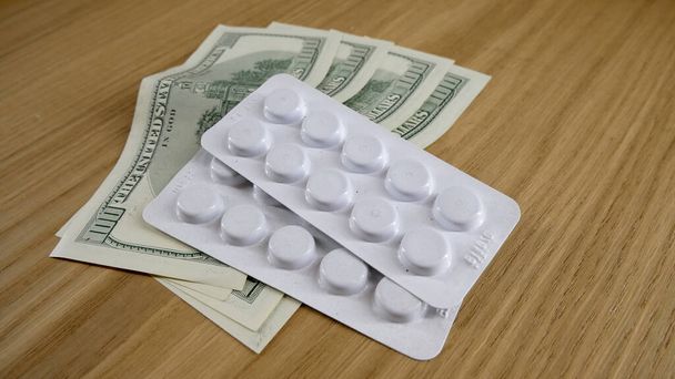 Таблетки на столі в білому пластику і доларах на столі
. - Фото, зображення