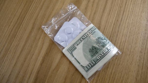 Dolarlarla dolu plastik bir çantada haplar. - Fotoğraf, Görsel