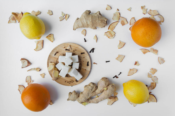 Fruit. Ginger orange lemon and lumps of sugar on a wooden saucer, all on a white background. - Foto, Imagem