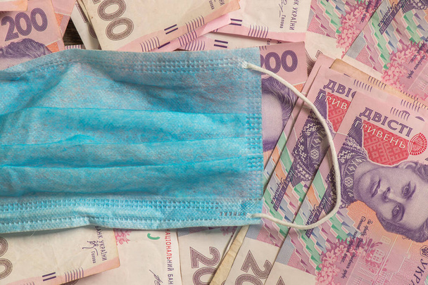 cash dollars en hryvnias en een medisch masker - Foto, afbeelding