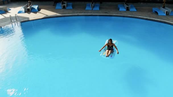 Drone flies over a pool in Egypt, where a woman swims on a mattress - Materiał filmowy, wideo