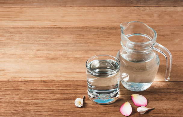Copo de água com frasco de vidro na mesa de madeira. Vidro e água potável limpa com espaço de cópia
. - Foto, Imagem