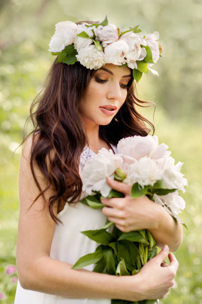 Spring portrait of young lady with wreath and bouquet of peonies in hands - Foto, Imagem