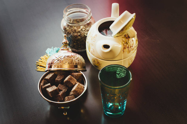 Tetera, azúcar, vasos de té y menta en una mesa marrón
 - Foto, imagen