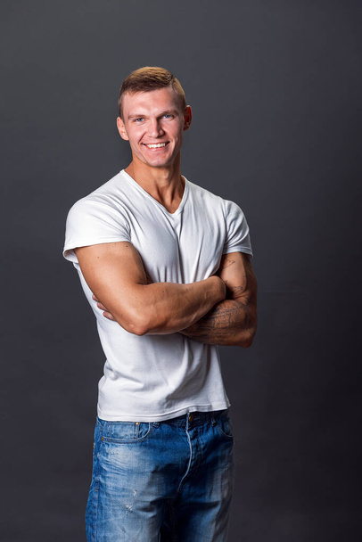 Smiling man in blank t-shirt, gray background - Foto, Imagem