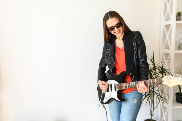 Woman in leather jacket playing an electric guitar - Foto, Imagem