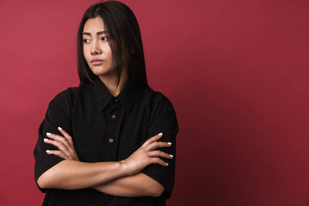 Close up of a pretty upset young asian woman wearing casual clothes standing isolated over red background - Foto, immagini