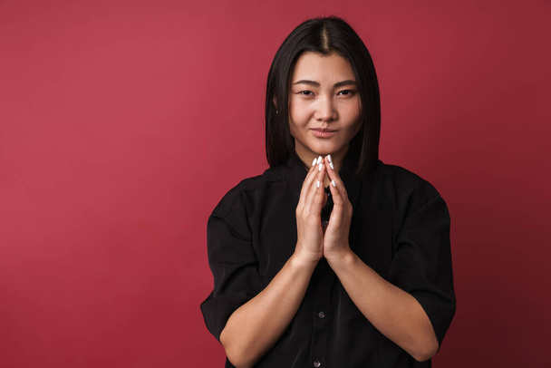 Close up of a pretty upset young asian woman wearing casual clothes standing isolated over red background - Fotó, kép