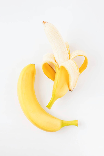 una banana amarilla madura pelada y sin pelar con una corteza bellamente envuelta sobre un aislado de fondo blanco
 - Foto, imagen