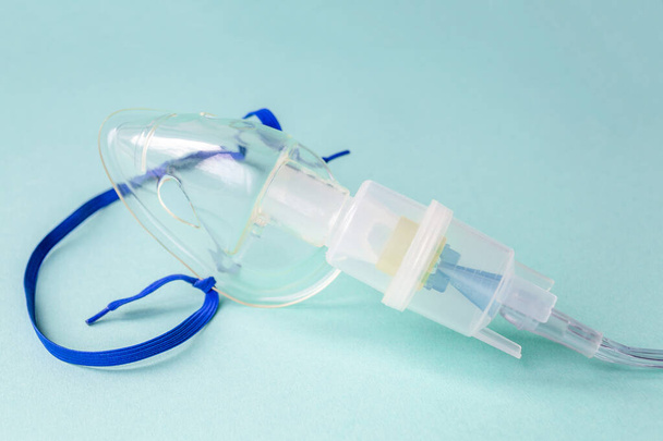 Blue background with device for inhalation of therapeutic steam. Transparent mask from inhaler.  - Foto, Imagen