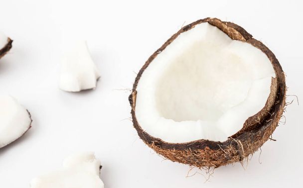 dojrzały kokos w skorupie z otwartym mięsem i kawałkami na białym izolacie tła - Zdjęcie, obraz