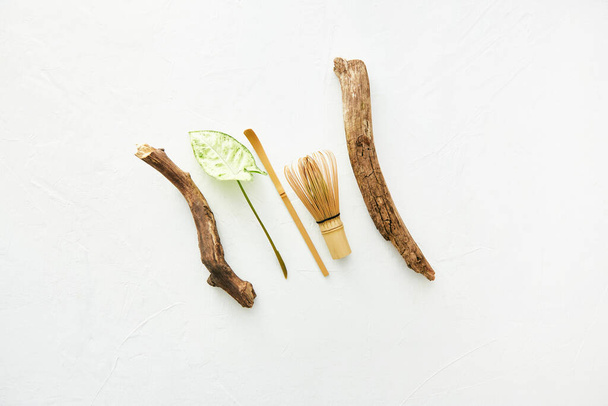 Batidor de bambú y cuchara de bambú chashaku para té matcha, palillos de madera y hojas aisladas en blanco
. - Foto, Imagen