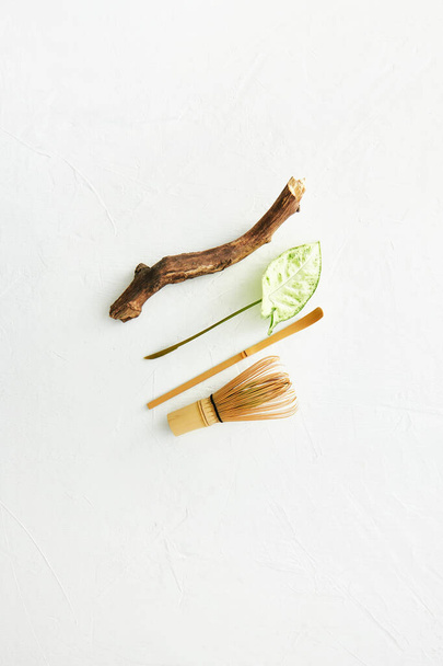 Bambusbesen und Chashaku-Bambuslöffel für Matcha-Tee, Holzstäbchen und Blatt. Weißer Hintergrund. - Foto, Bild