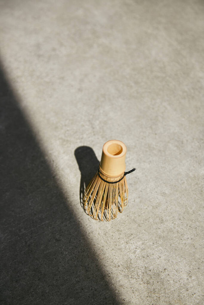 Bambusová šlehačka Matcha se stínovým úhlem na šedém povrchu. - Fotografie, Obrázek