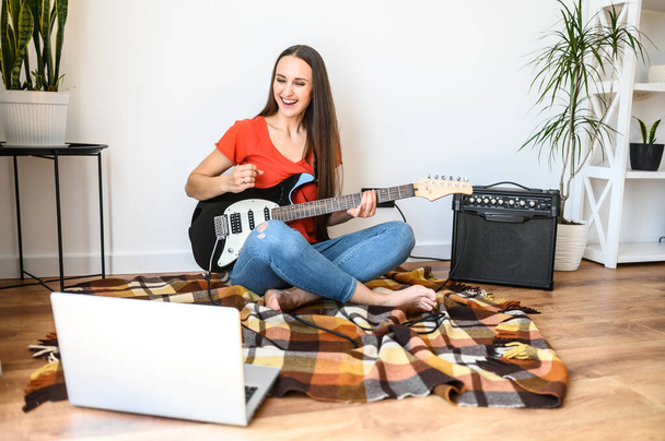 Young woman learns to play the electric guitar - Photo, Image