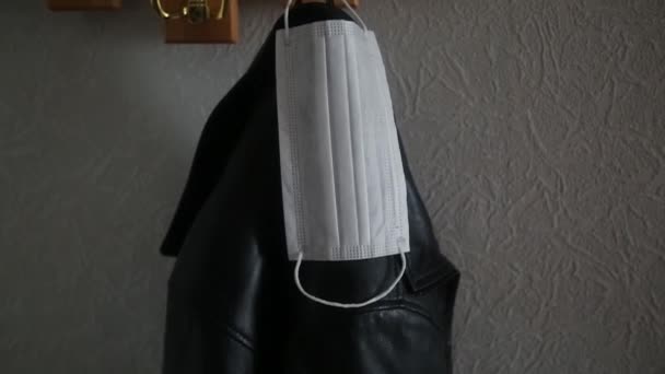 Beschermende masker tegen whist virus op een hanger. Een masker om het ademhalingssysteem te beschermen tegen het coronavirus hangt aan het jasje toegang tot de straat zonder masker is verboden - Video