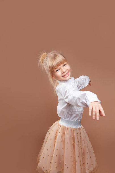 little girl dancing on a beige background - Фото, зображення