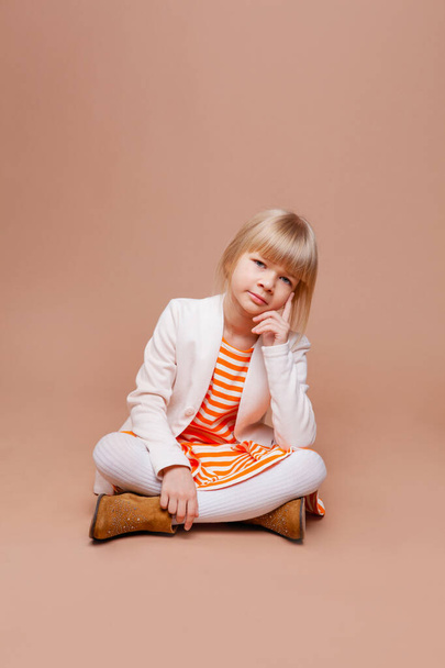 χαριτωμένο κορίτσι σε καθημερινά φθινοπωρινά ρούχα σε μπεζ φόντο - Φωτογραφία, εικόνα