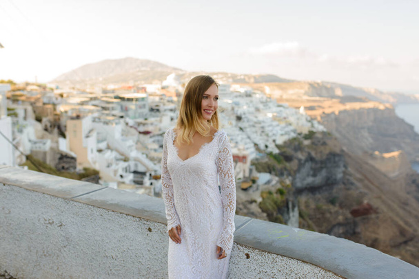 Krásná nevěsta v bílých šatech pózující na pozadí města Thira, Santorini. - Fotografie, Obrázek
