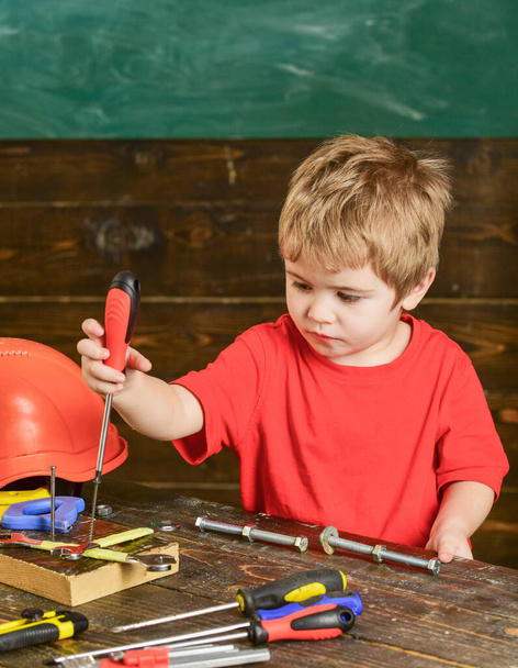 Little repairman in workshop. Boy binding screws to wooden board. Kid playing with instruments - Foto, Bild