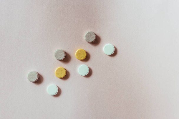eight round tablets of different colors lie on the background. Calcium, vitamins, prevention. treatment of heart flu. coronovirus. Immunity Sports Nutrition. Top view, close-up, selective focus. - 写真・画像