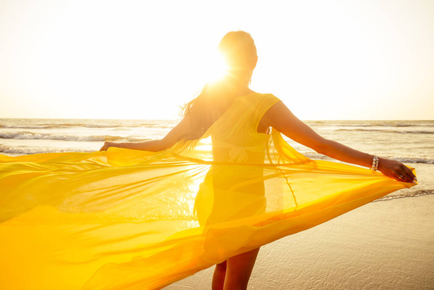 woman in amazing yellow dress feeling free and happy yo be at ocean - Фото, изображение