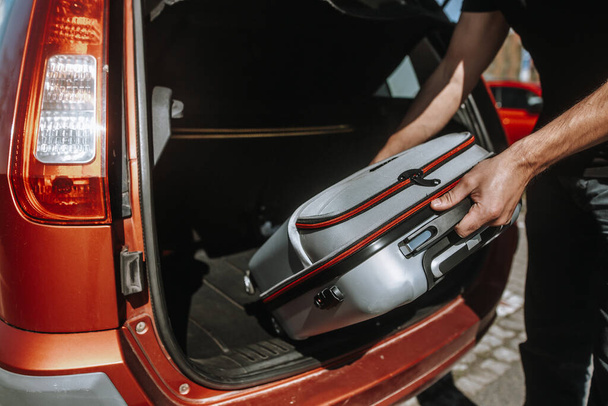 Homem de negócios, empregado se preparando para viagem de negócios ao exterior, coloca bagagem no porta-malas de um carro
 - Foto, Imagem