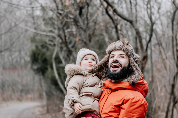 happy family concept. Father and baby daughter playing and laughing on cold winter walk in par - Zdjęcie, obraz