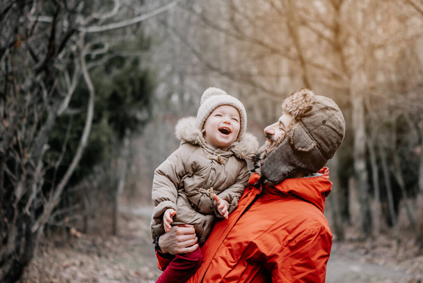 happy family concept. Father and baby daughter playing and laughing on cold winter walk in par - 写真・画像