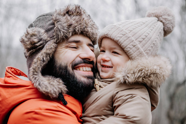 Portrait of happy family: Father and baby daughter on Winter Vacation in park. Happy, joyful family. - Photo, Image