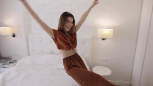 Joyful woman in pajama falling down on bed - Filmati, video