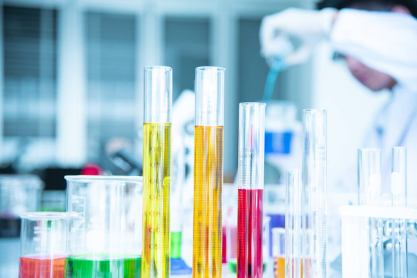 Laboratuvar masasında kimyasal arka plan için farklı renklerde sıvılar bulunan bir bilim laboratuarında çeşitli test tüpleri ve solüsyon şişeleri var. - Fotoğraf, Görsel