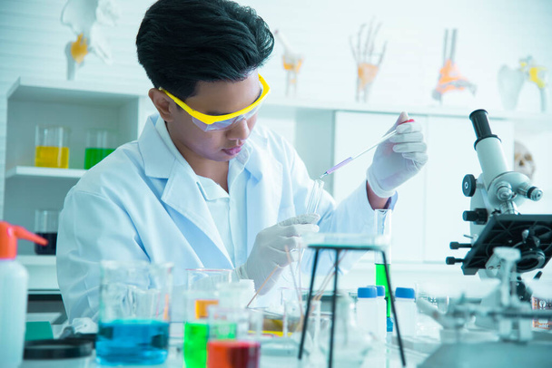 Junge asiatische Wissenschaftler erforschen und testen den Einsatz von Chemikalien für die Produktion. Siehe Reagenzgläser in wissenschaftlichen Labors, Erfindungen und Forschungskonzepten. - Foto, Bild