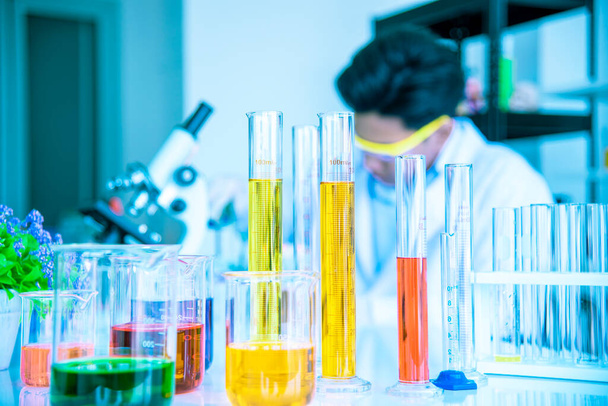 Test tubes and solution beakers in a science laboratory with a multicolored liquid on the laboratory table for a chemical background Concept Search - Photo, Image