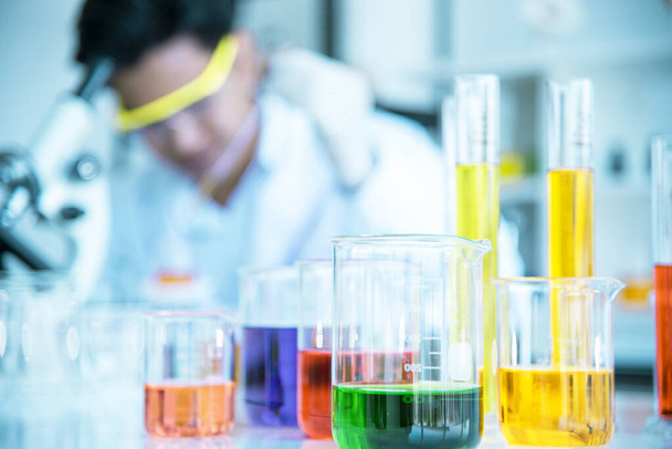 Test tubes and solution beakers in a science laboratory with a multicolored liquid on the laboratory table for a chemical background Concept Search - Photo, Image