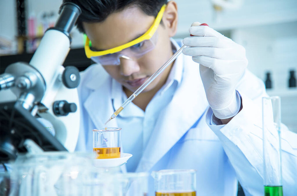 Aasialainen nuori tiedemies tutkii ja testaa kemikaalien käyttöä tuotannossa. Katso koeputket tieteen laboratorioissa, keksinnöissä ja tutkimuskonsepteissa
. - Valokuva, kuva