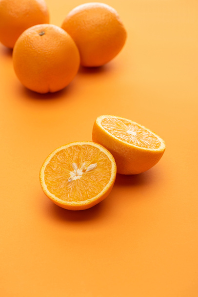 selective focus of ripe juicy whole and cut oranges on colorful background - Foto, Imagem