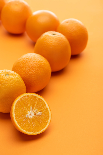 selective focus of ripe juicy whole and cut oranges on colorful background - Φωτογραφία, εικόνα