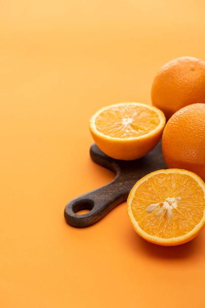 ripe juicy whole and cut oranges on wooden cutting board on colorful background - Photo, Image