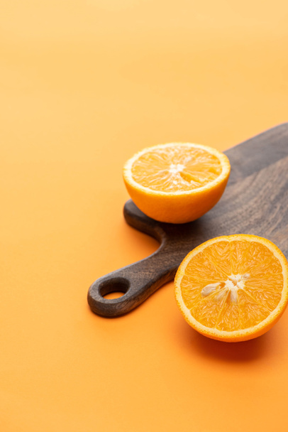 ripe juicy orange halves on wooden cutting board on colorful background - Foto, Imagem