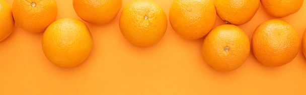 bovenaanzicht van rijpe sappige hele sinaasappels op kleurrijke achtergrond met kopieerruimte, panoramisch shot - Foto, afbeelding