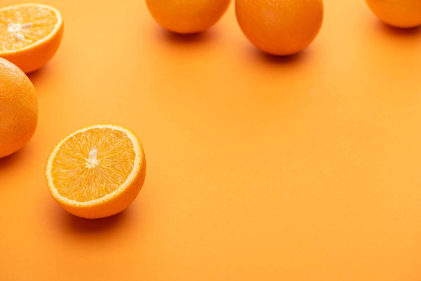 selective focus of ripe juicy whole and cut oranges on colorful background - Foto, Imagen